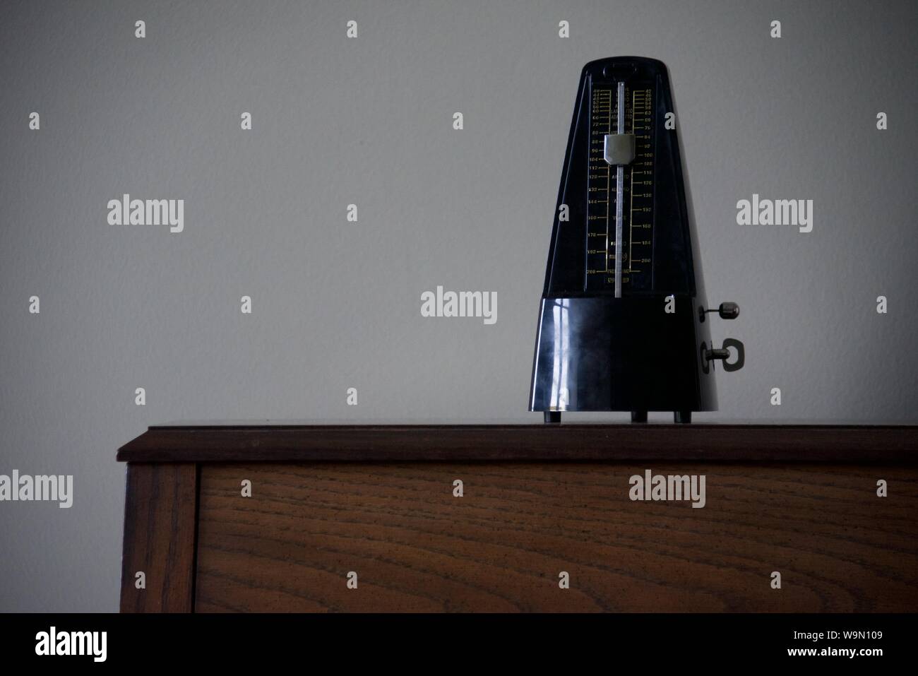 Metronome: a silent metronome sat upon the top of an upright piano Stock Photo