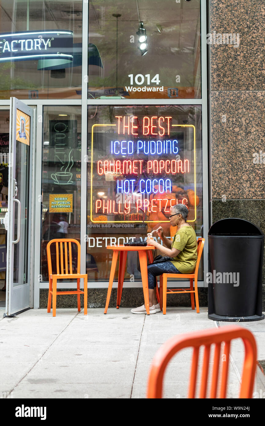 Detroit, Michigan - A woman sits at an outdoor table at the Detroit Water Ice Factory. The store sells desserts and snacks, with all profits going to Stock Photo