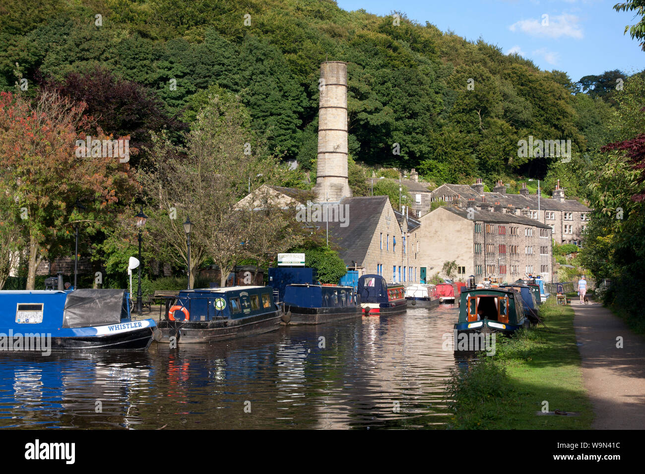 narrowboats on the Rochdale Canal at Hebden Bridge with old chimney of Crossley Mill in the distance, Upper Calder Valley, West Yorkshire Stock Photo