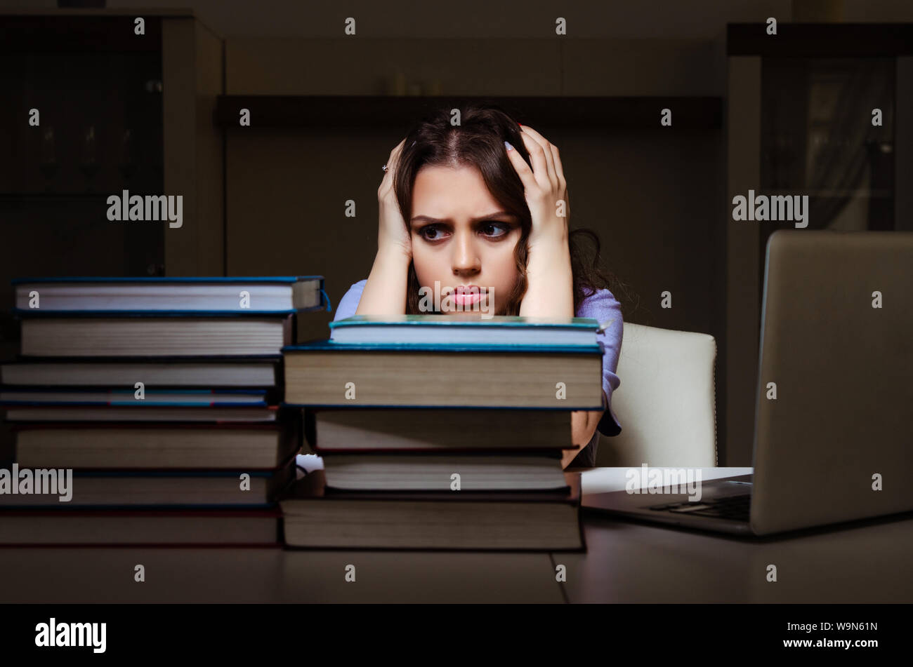 The young female student preparing for exams late at home Stock Photo ...