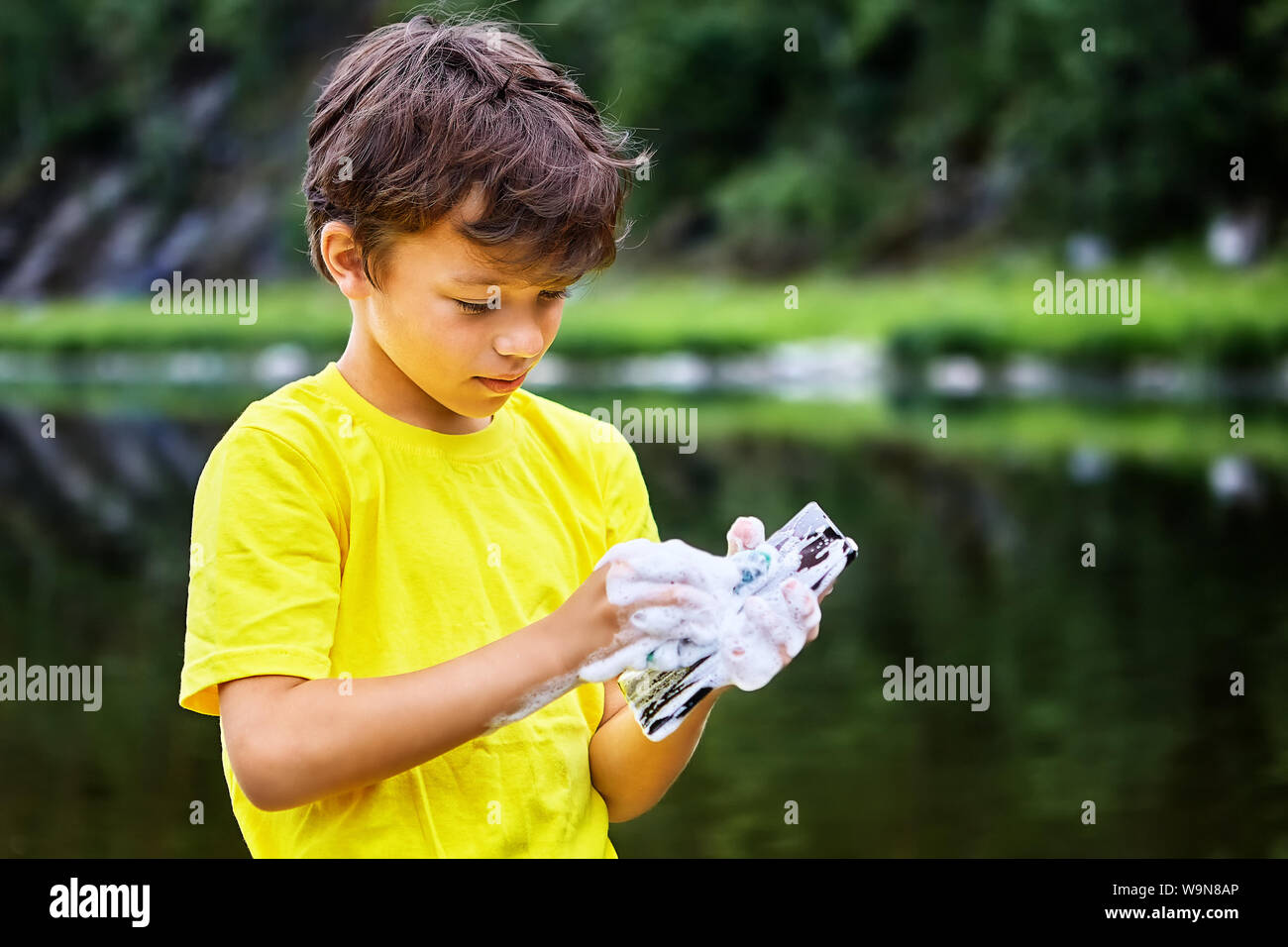 Removing dirt from the screen of a mobile phone. Little boy cares for a