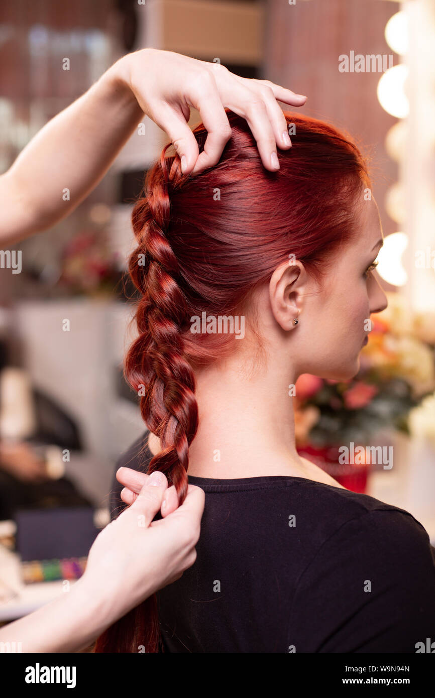 Beautiful, red-haired girl with long hair, hairdresser weaves a French  braid, in a beauty salon. Professional hair care and creating hairstyles  Stock Photo - Alamy