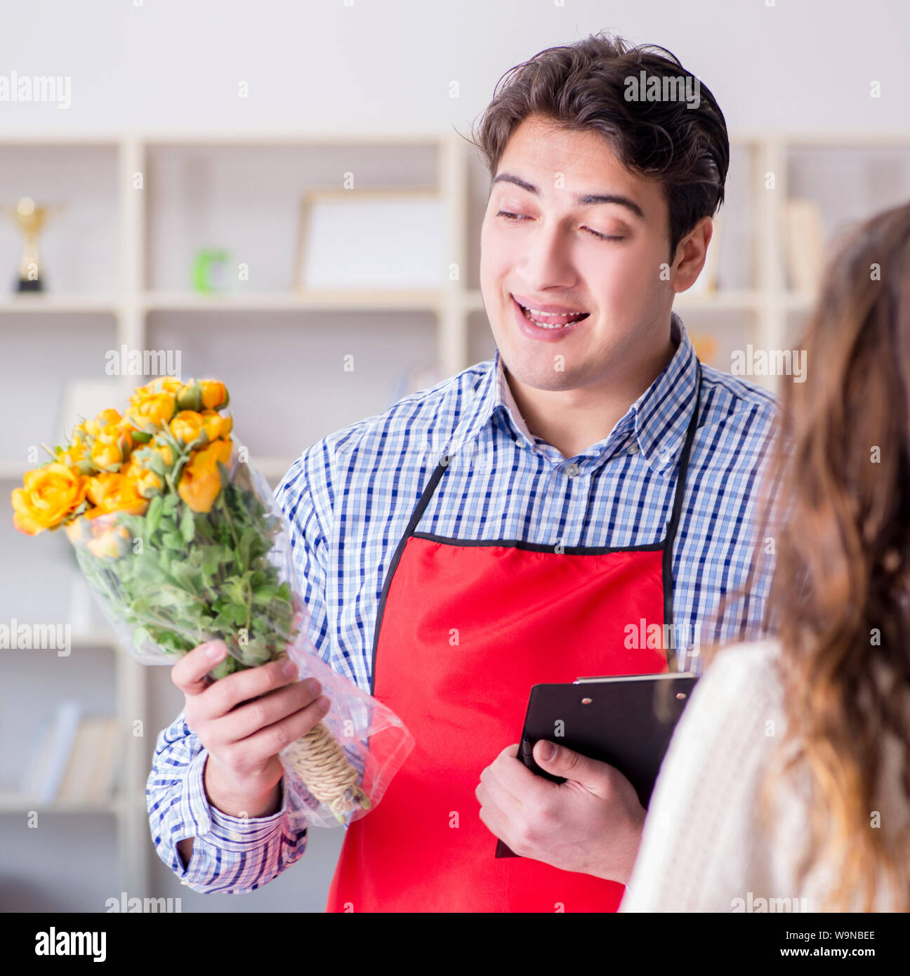 The flower shop assistant selling flowers to female customer Stock