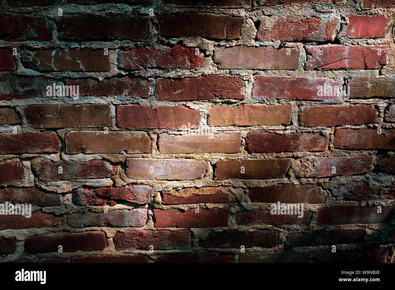 a close up of light and shadow falling  across  an old, fading, red brick wall Stock Photo