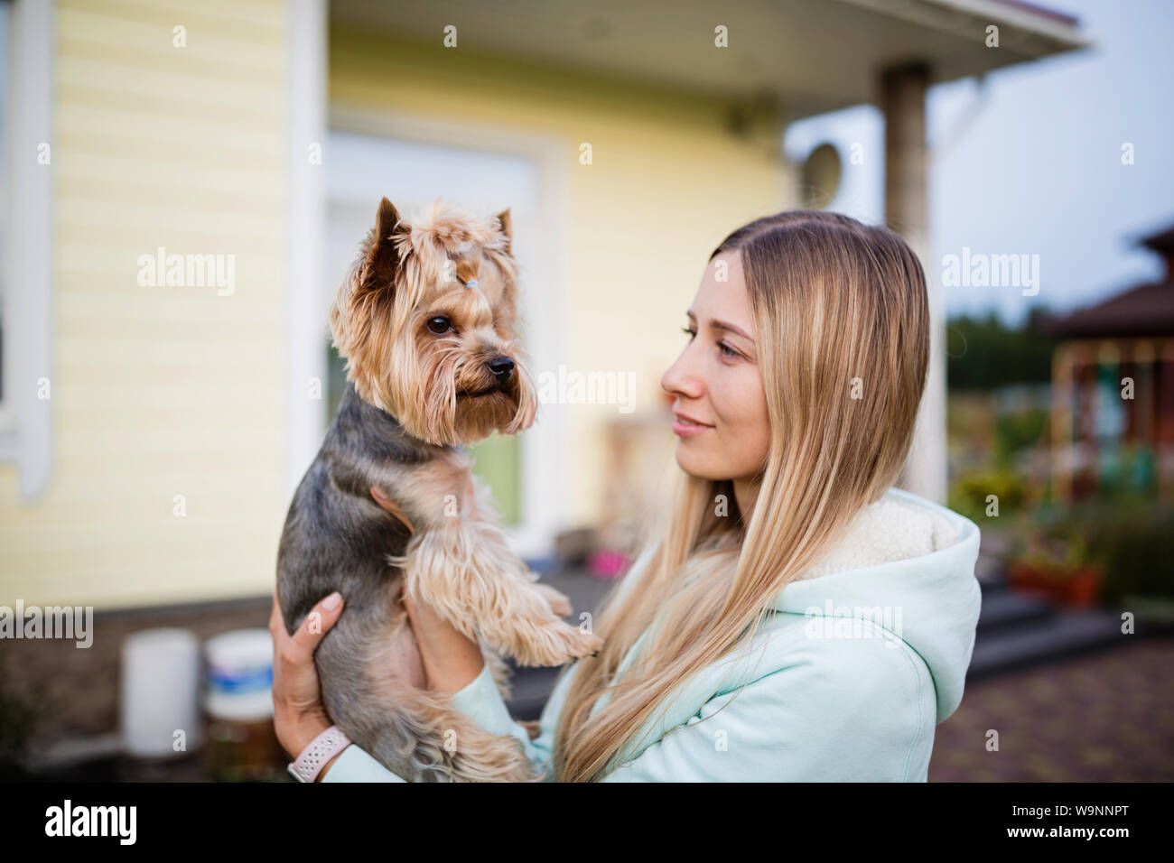 pretty woman with long blonde hair holding small dog yorkshire