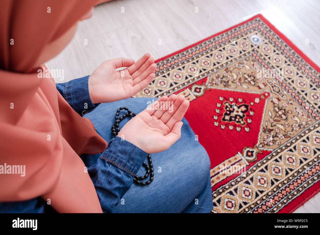 Muslim woman prayer, muslim girl open hands praying with rug Stock Photo