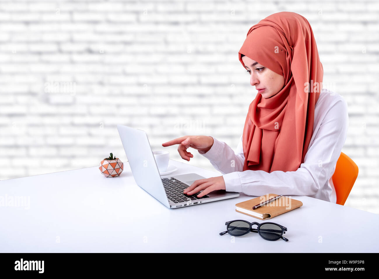 Muslim woman work with computer in office, hijab muslim girl pointing laptop screen Stock Photo