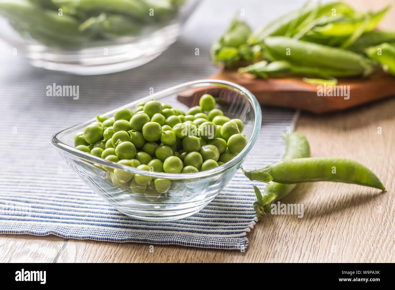 Fresh green pea seeds in bowl on kitchen table Stock Photo