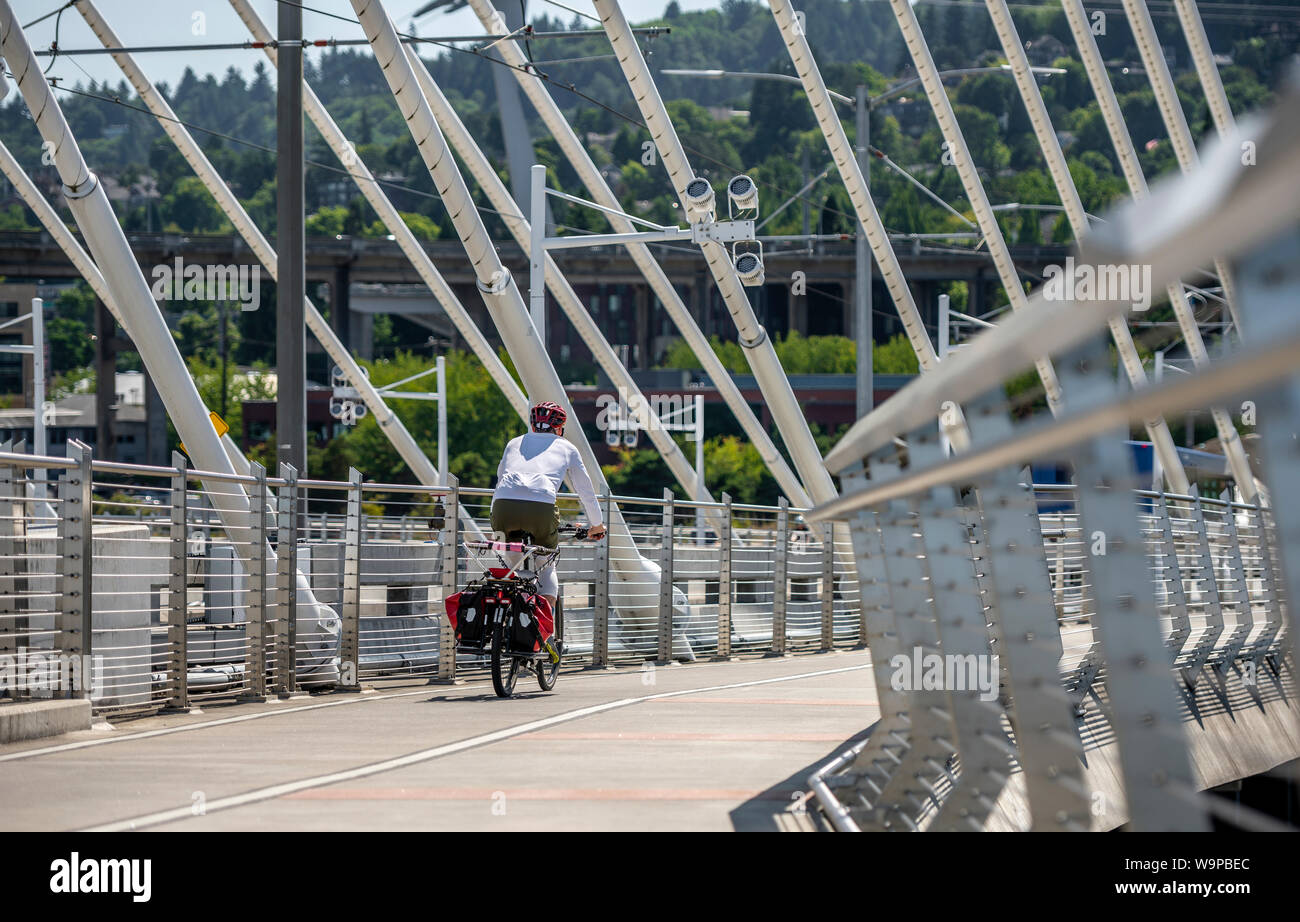 Man Cyclist in sports outfit rides a bicycle on the Tilikum Crossing Bridge. The use of a bicycle as the main transport for many enthusiasts has grown Stock Photo