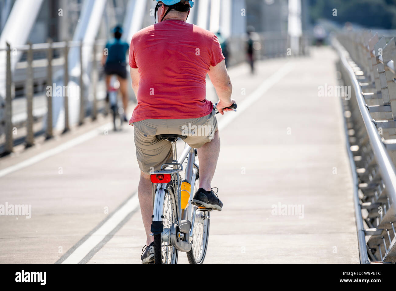 An elderly Man cyclist pedals a bicycle and rides along the Tilikum Crossing Bridge, preferring like most Portland residents an active healthy lifesty Stock Photo