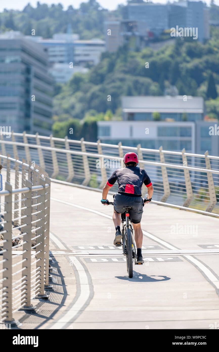 Man Cyclist in sports outfit rides a bicycle on the Tilikum Crossing Bridge. The use of a bicycle as the main transport for many enthusiasts has grown Stock Photo