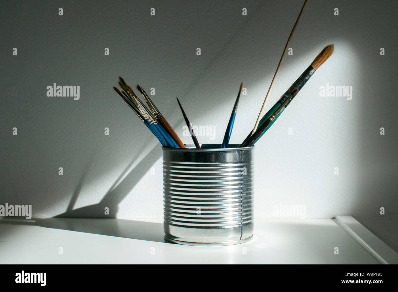 Tin can with paint brushes closeup on white wall background Stock Photo