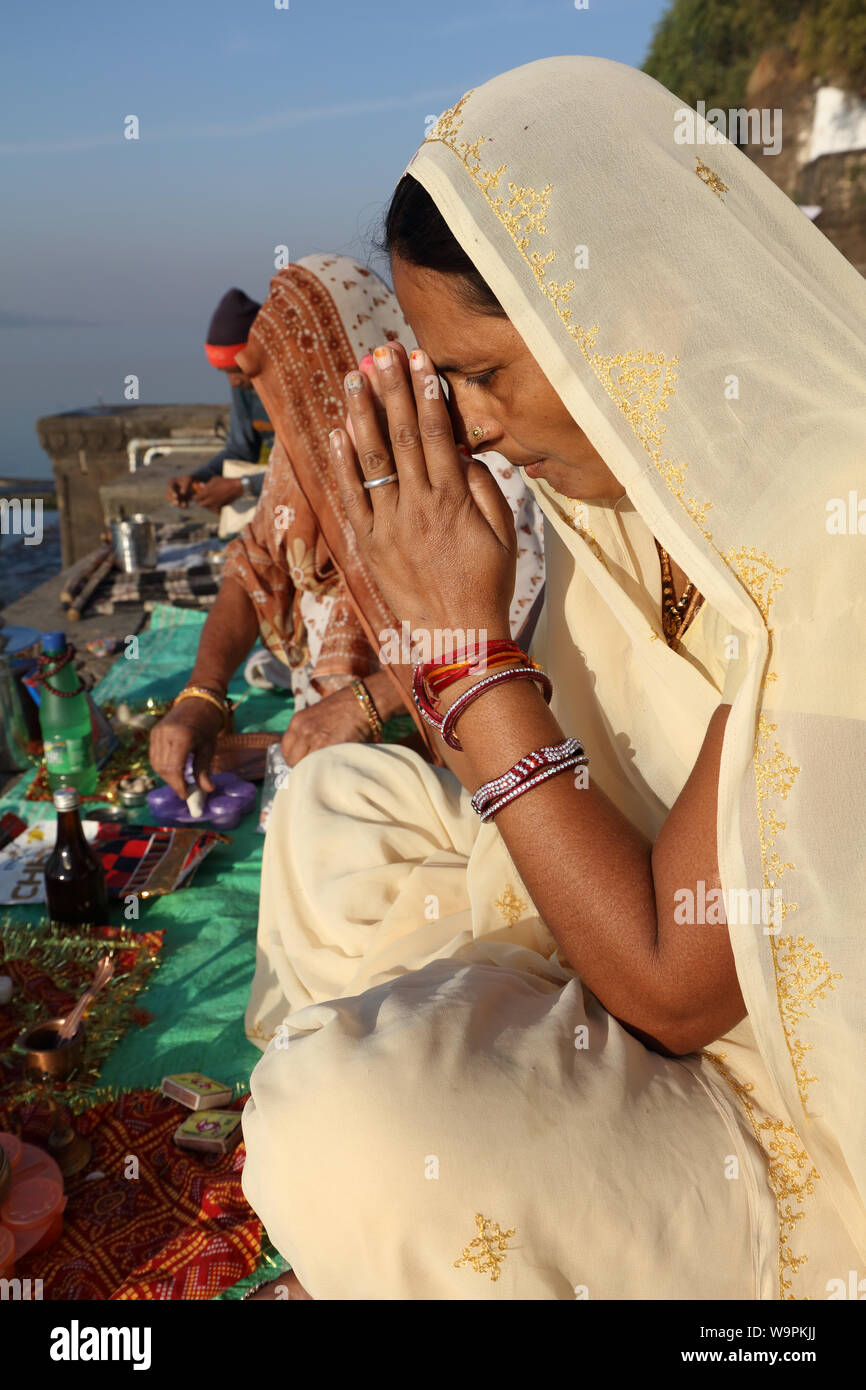 Devout Hindu pilgrim prays on the ghats of the sacred river Narmada in Maheshwar, India Stock Photo