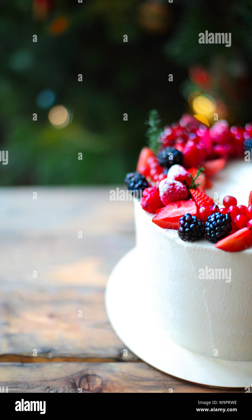 Christmas Cake decorated with berries by the Christmas tree Stock Photo