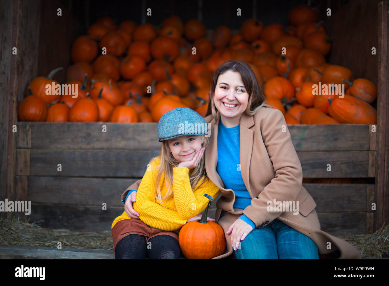 Happy little girl with her mother at the autumn pumpkin patch ...