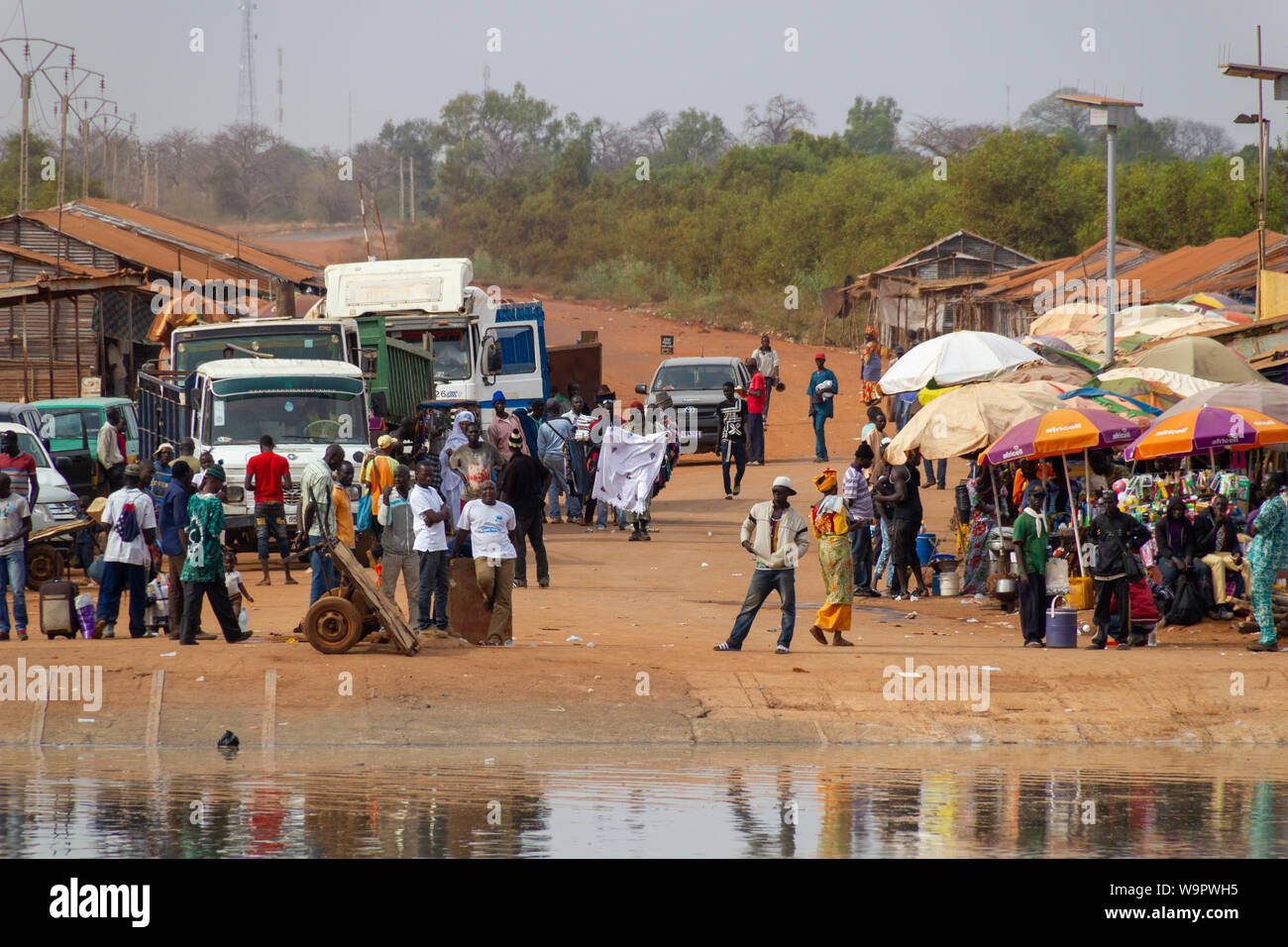 BAMBA TENDA, GAMBIA- JAN 6, 2014: Waiting people for the ferry. Also markets that sell everything around ferry docking places Stock Photo