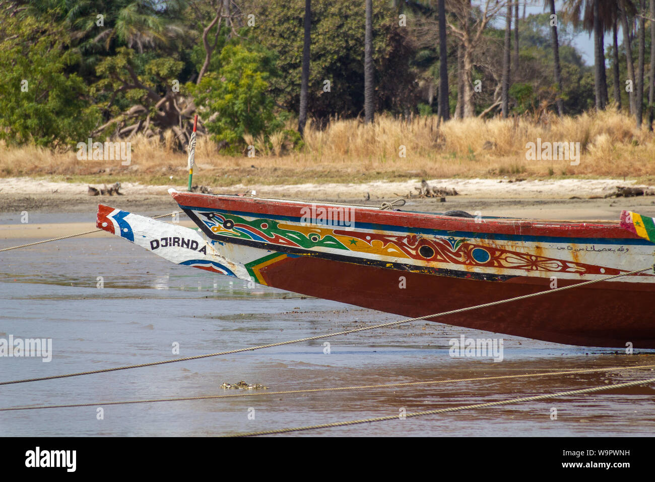 JUFUREH, GAMBIA- JAN 12, 2014: The front of the boat is colorfull and well painted. Boats are self made of what nature gives. Long trees are used Stock Photo