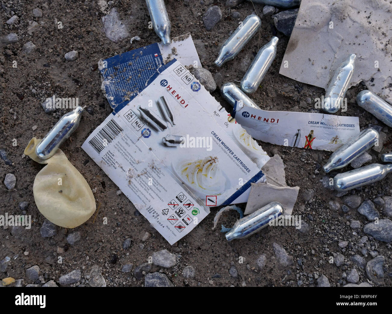 Used Nitrous Oxide canisters and a balloon discarded on a car park in Bolton, North West England UK.  photo Don Tonge Stock Photo