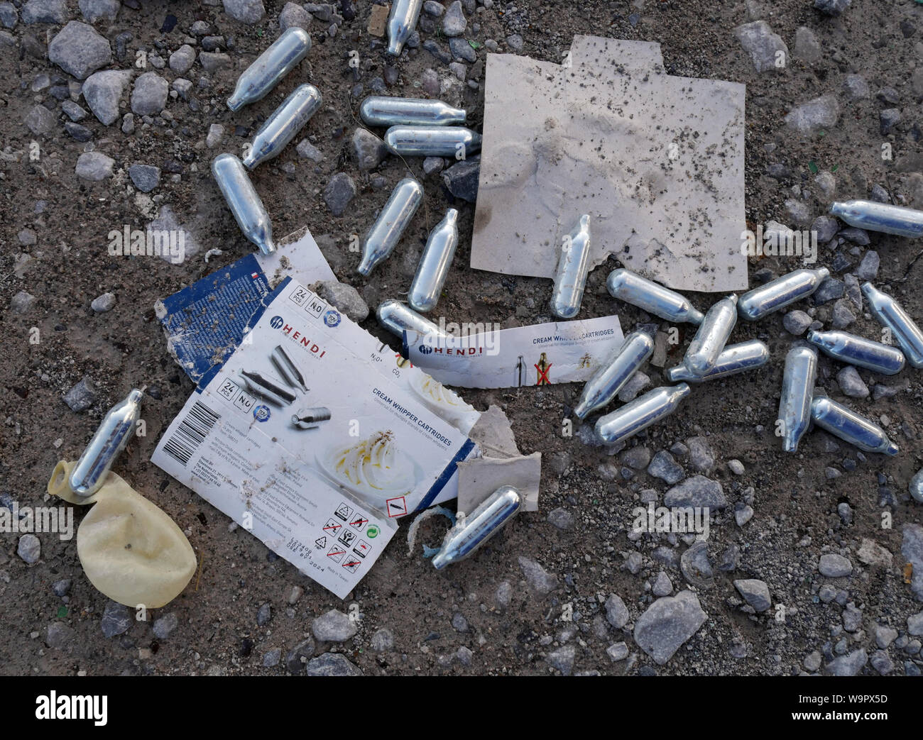 Used Nitrous Oxide canisters and a balloon discarded on a car park in Bolton, North West England UK.  photo Don Tonge Stock Photo