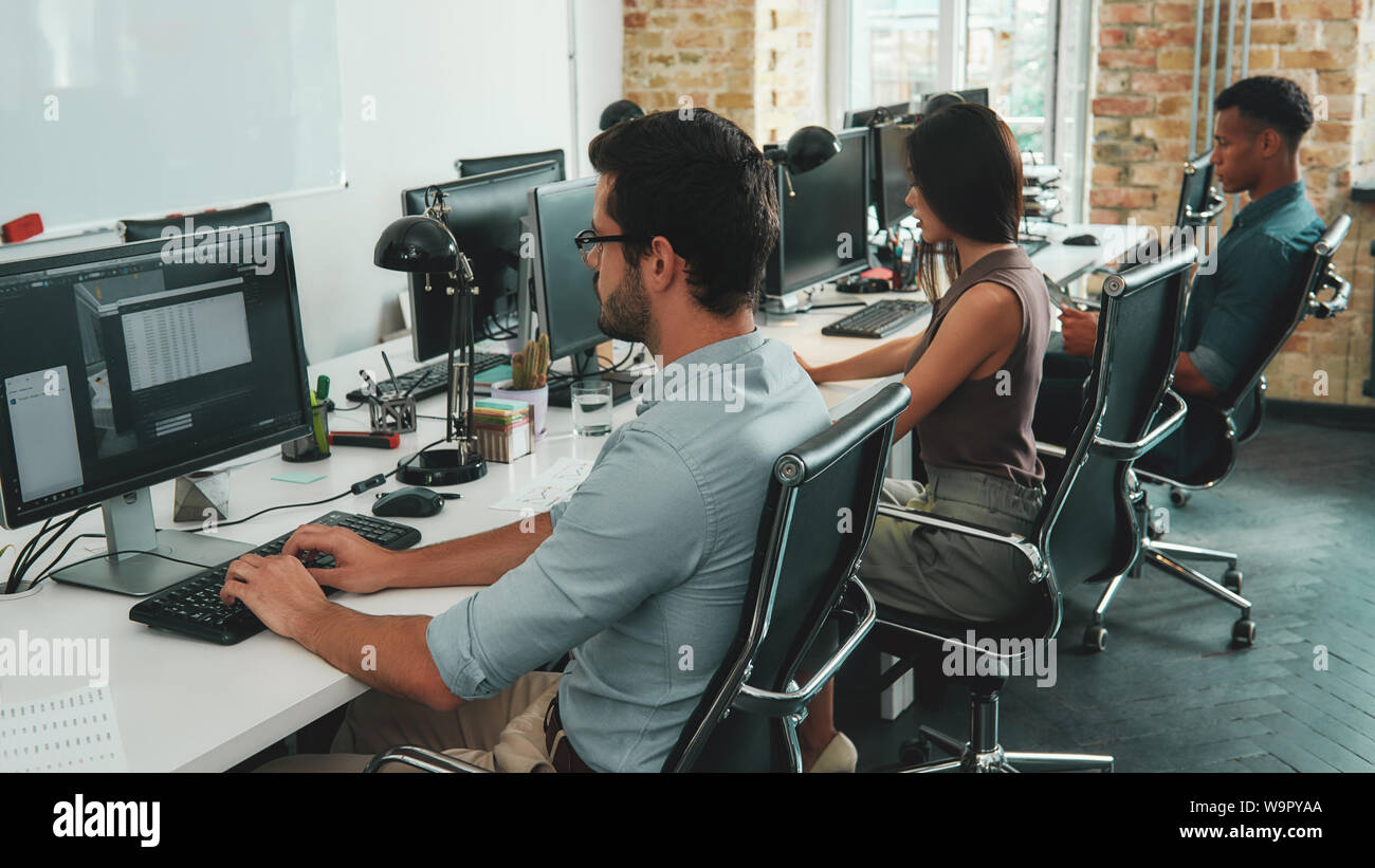 Multiracial team. Back view of busy employees working on computers