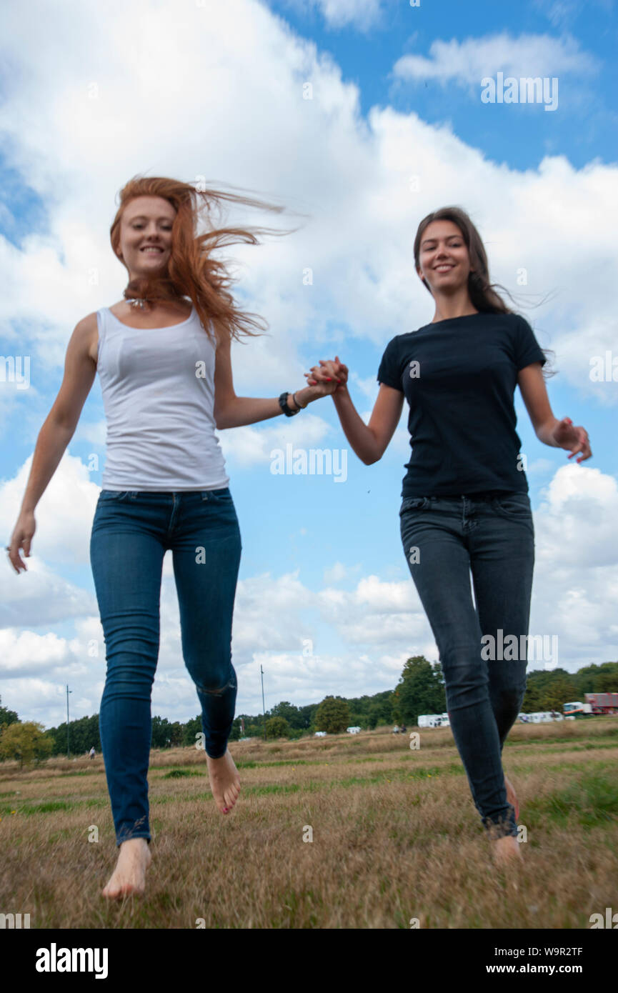 Tennage girls running holding hands sunny day Stock Photo - Alamy