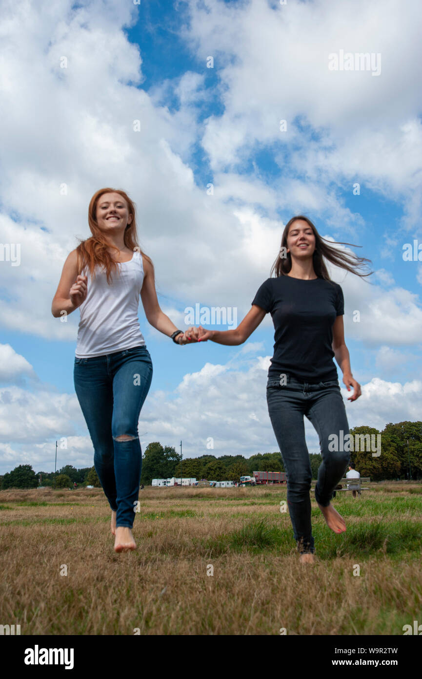 Tennage girls running holding hands sunny day Stock Photo - Alamy