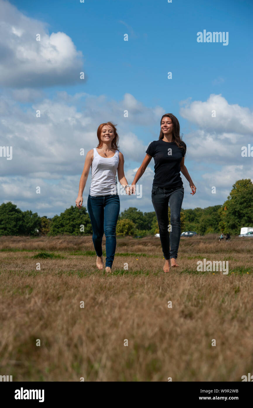 Tennage girls running holding hands sunny day Stock Photo - Alamy