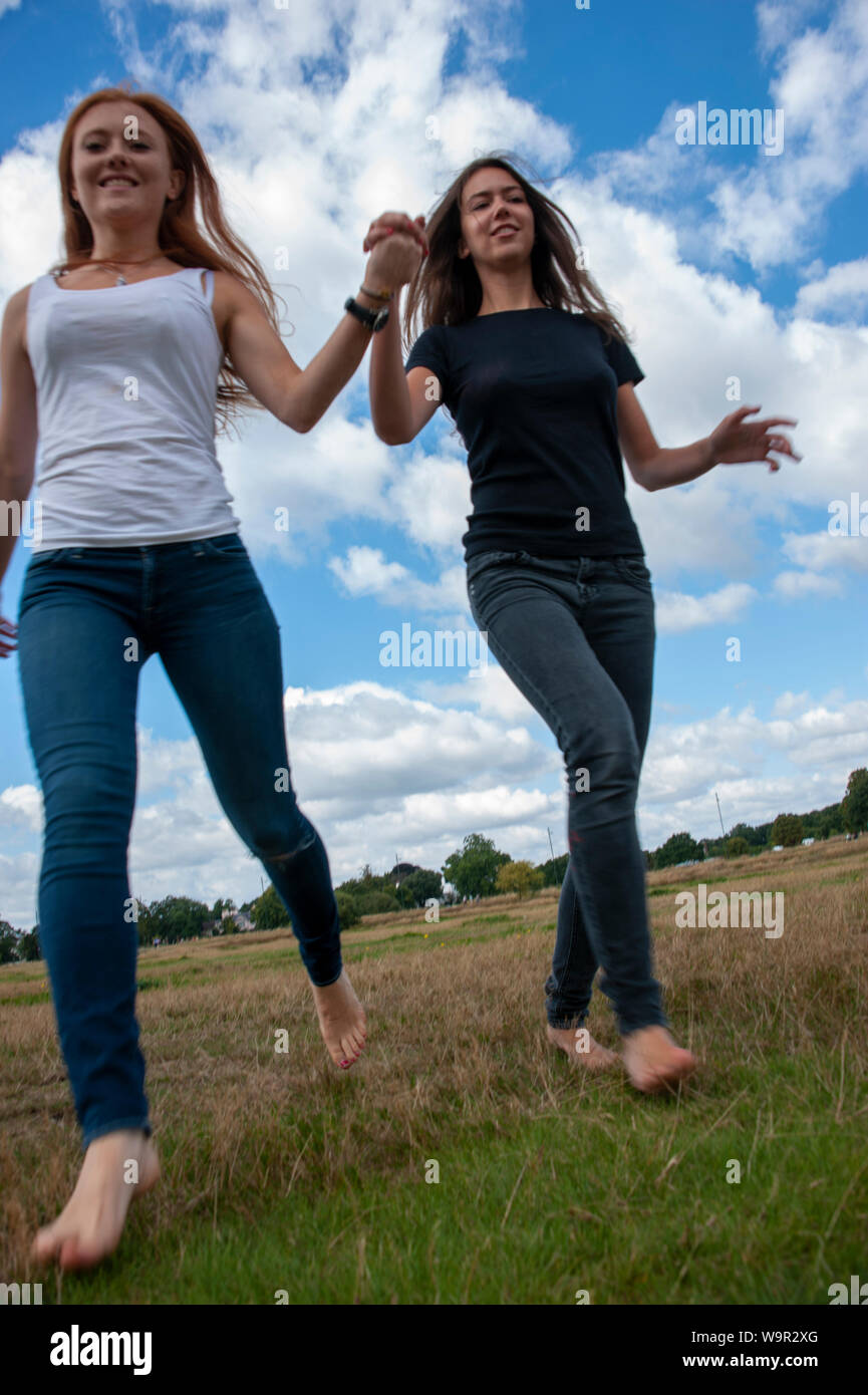 Tennage girls running holding hands sunny day Stock Photo - Alamy