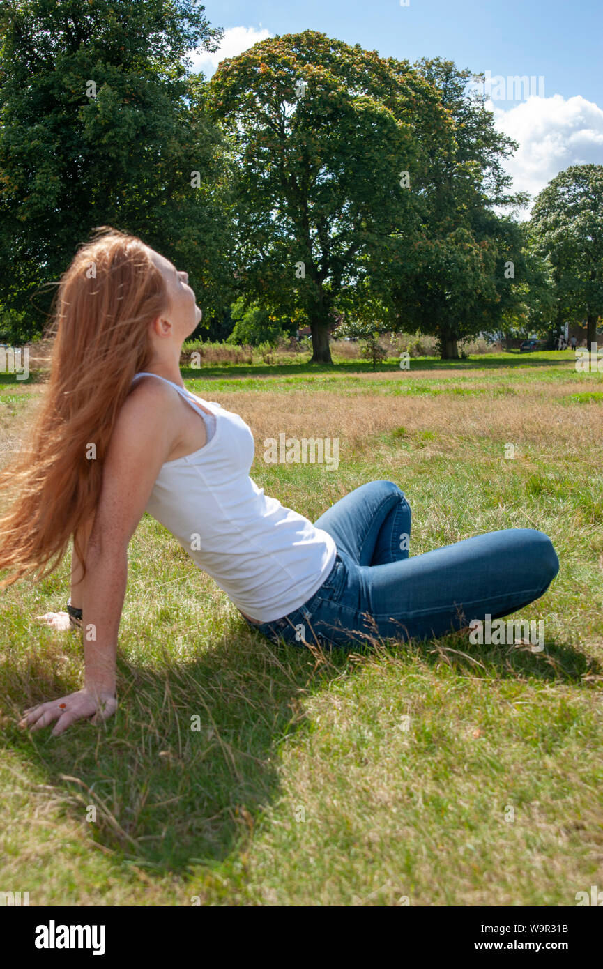 Tennage Girl Red Hair Freckles Sits Back On Grass Relaxed Face To Sun