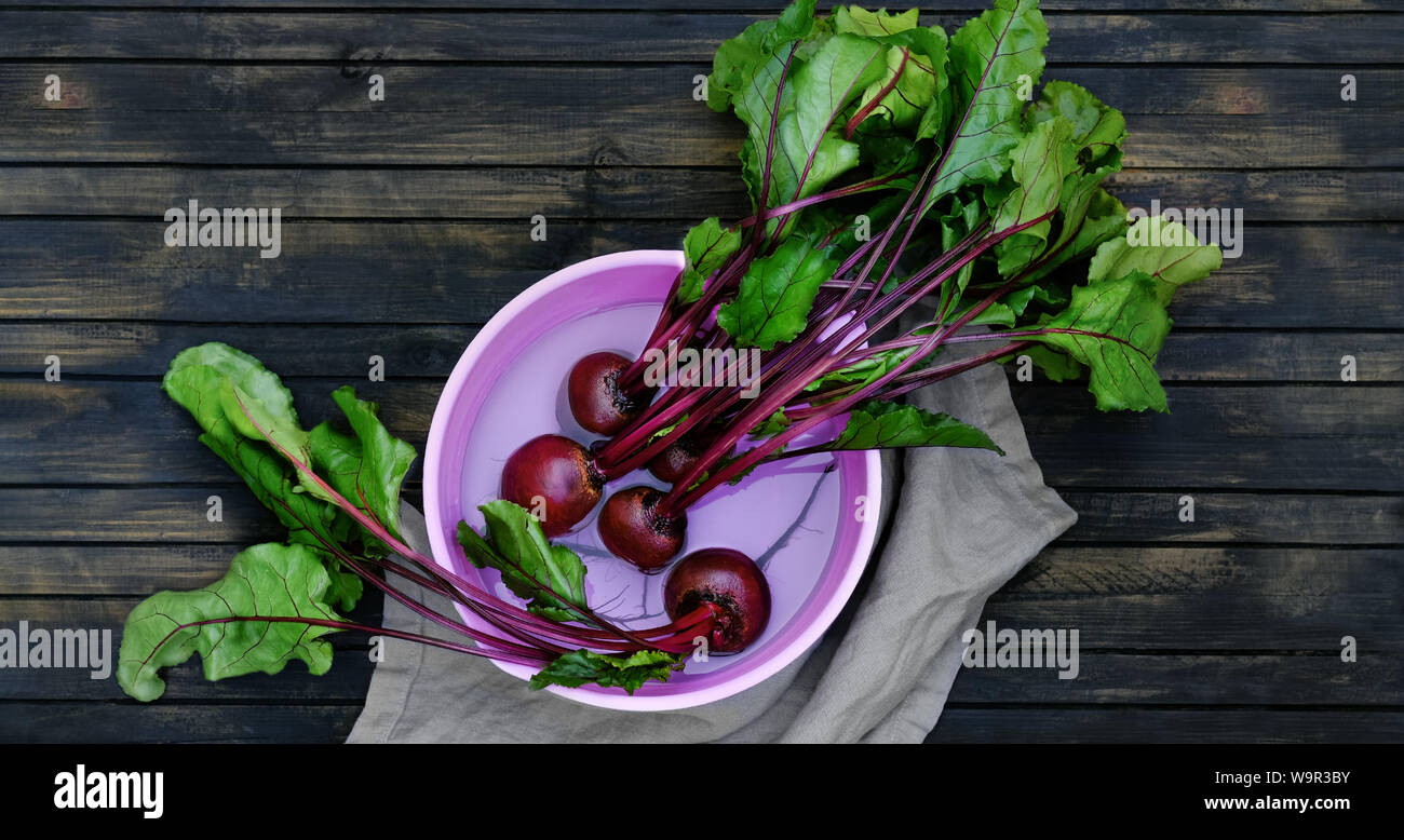 Beets in rinsing. beetroot is a helthy food and is rich in antioxidants and vitamins. Roots in a water bowl on a dark wood table. Stock Photo