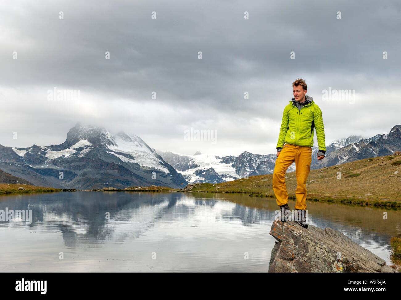 Hiker stands on rock, Lake Stellisee, behind Matterhorn, cloudy, Wallis, Switzerland Stock Photo