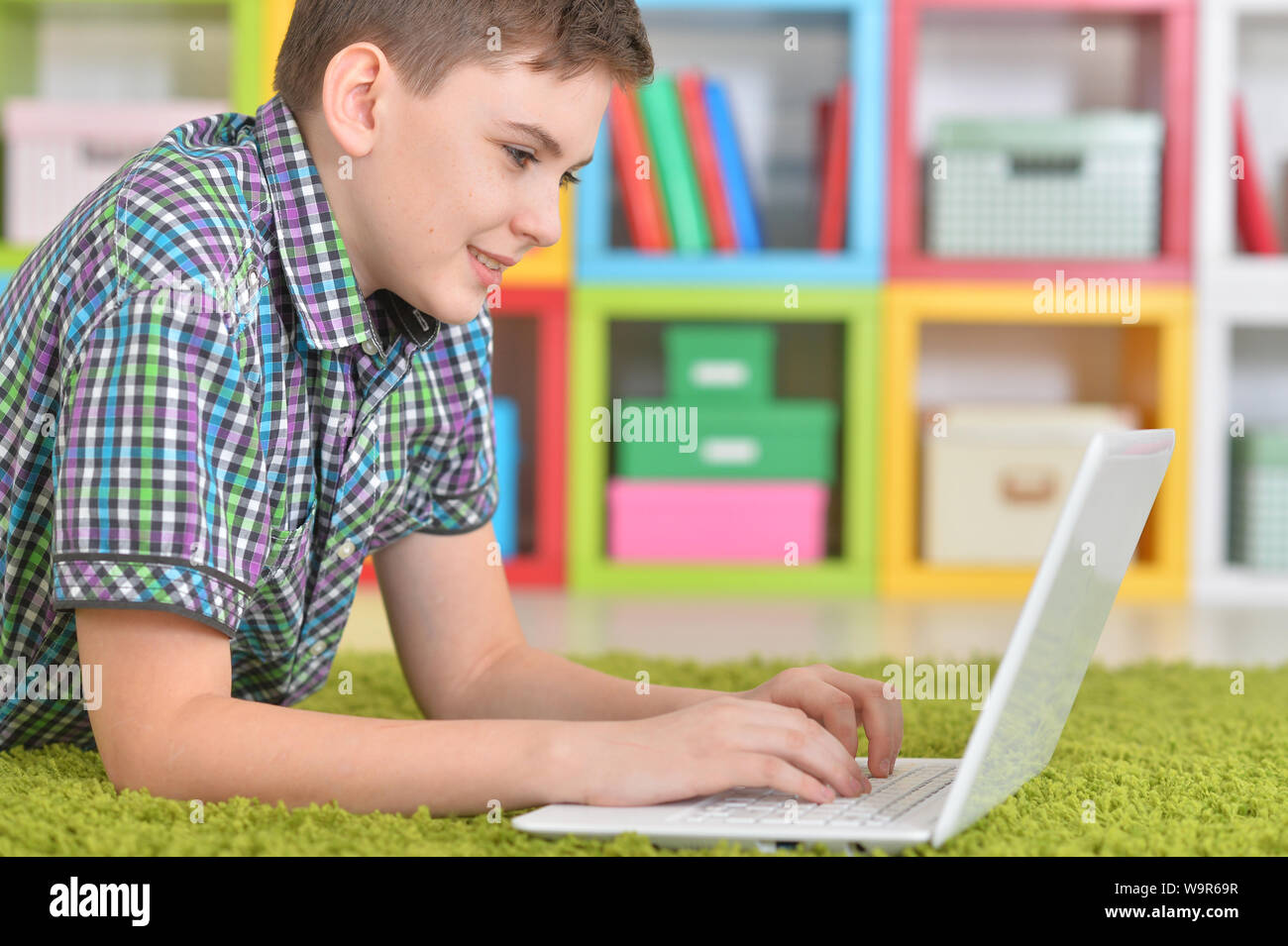Little boy using laptop while lying on floor at home Stock Photo - Alamy