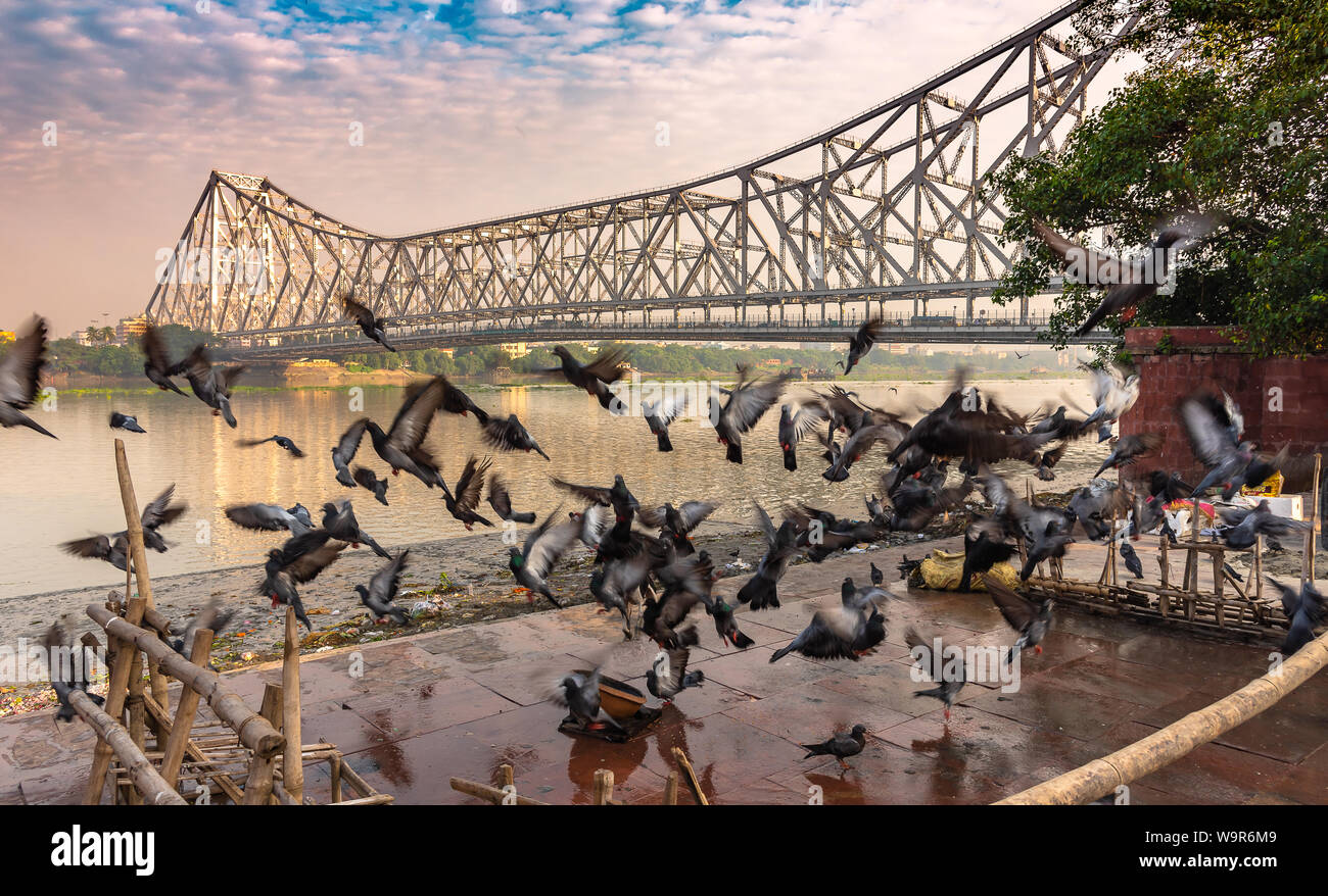 Silhouette of People , taking Holy bath in River Ganges overlokking the Howrah Bridge, a bridge with a suspended span over the Hooghly River in West B Stock Photo