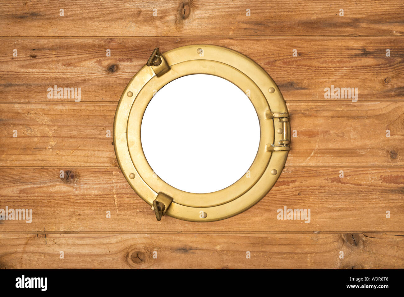 Vintage brass porthole in wooden wall, window isolated with clipping path Stock Photo