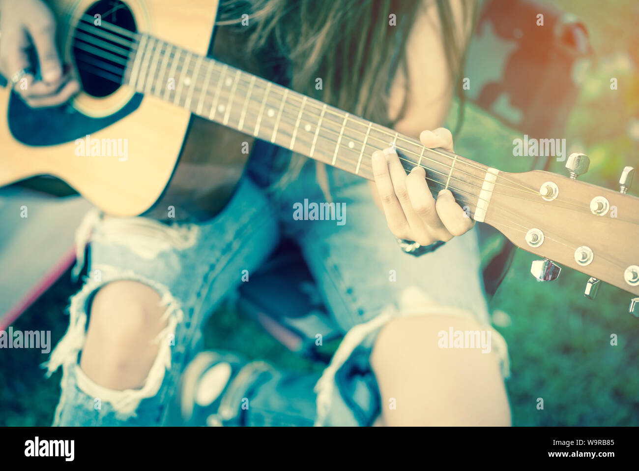 closeup of female's hands playing acoustic guitar with vintage tone Stock Photo