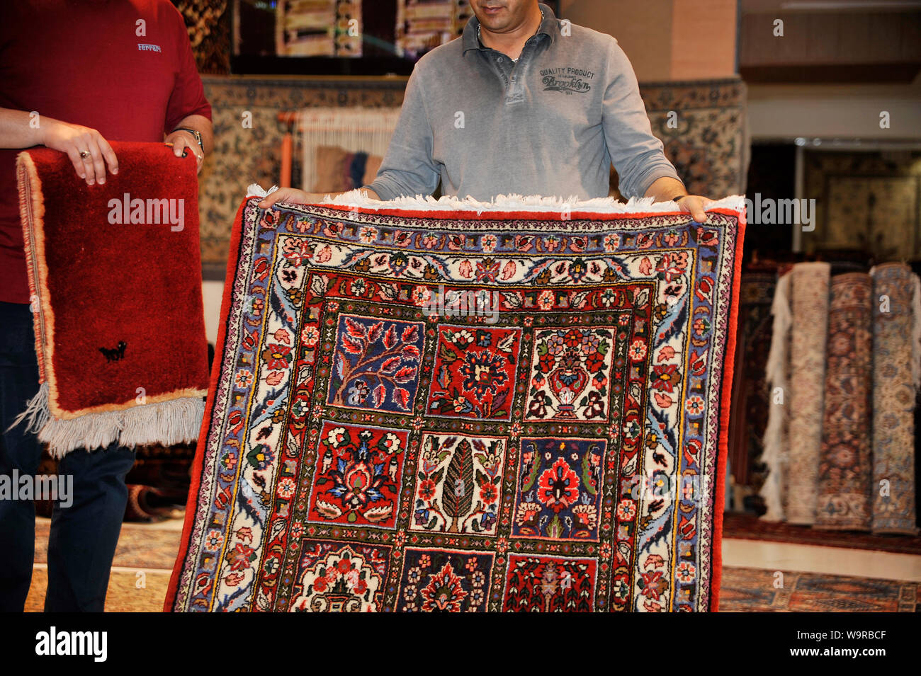 Carpets seller showing products, Iran Stock Photo - Alamy