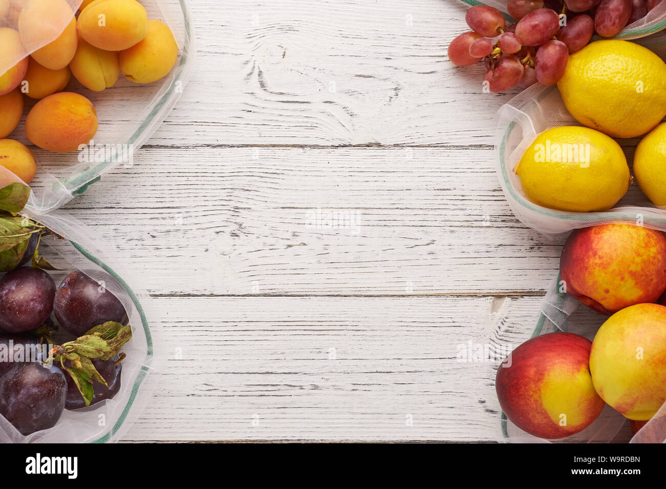 Fruits in reusable eco bags at white wooden background. Recycled bags ...