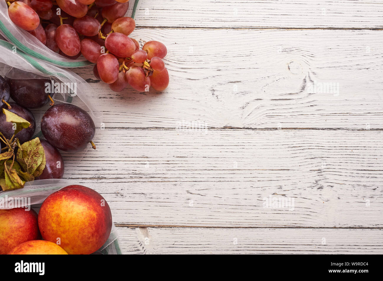 Fruits in reusable eco bags at white wooden background. Recycled bags ...
