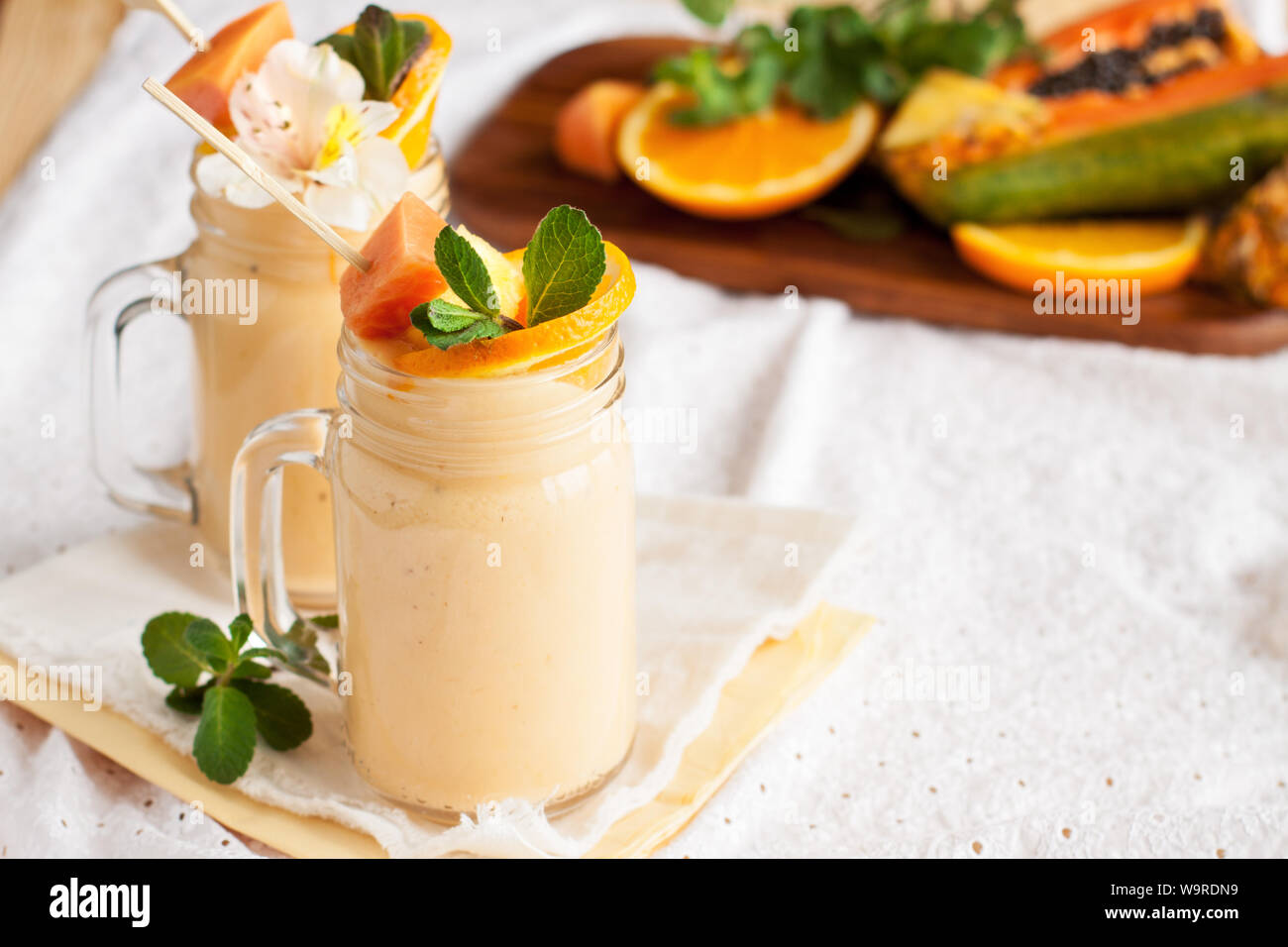 Homemade smoothie with tropical fruits: mango, banana, pineapple, papaya in glass Mason jar. Healthy juicy vitamin drink Stock Photo
