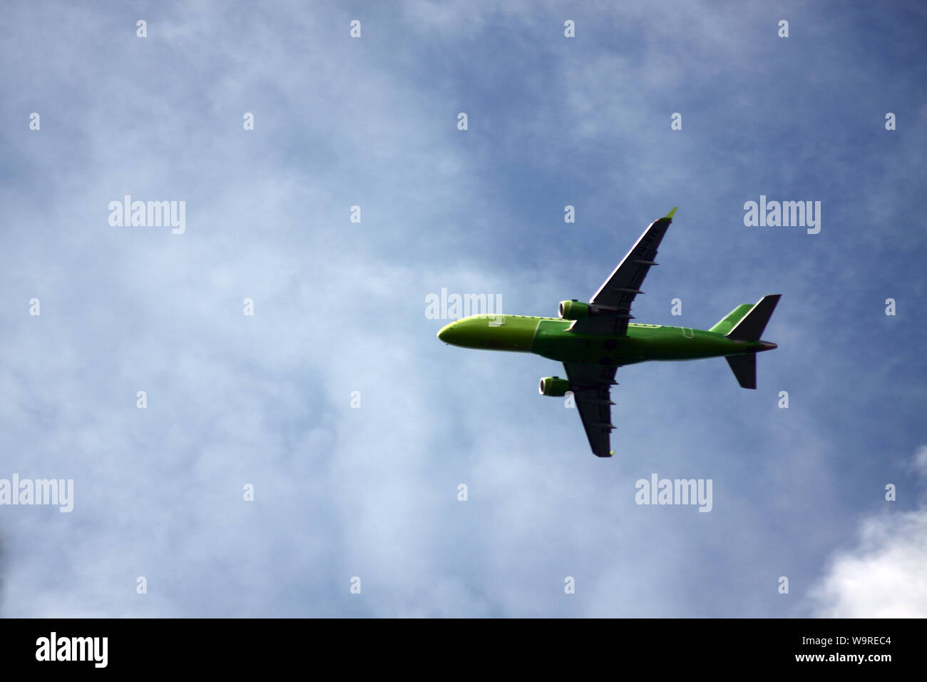 airplane flying in cloudy blue sky Stock Photo - Alamy
