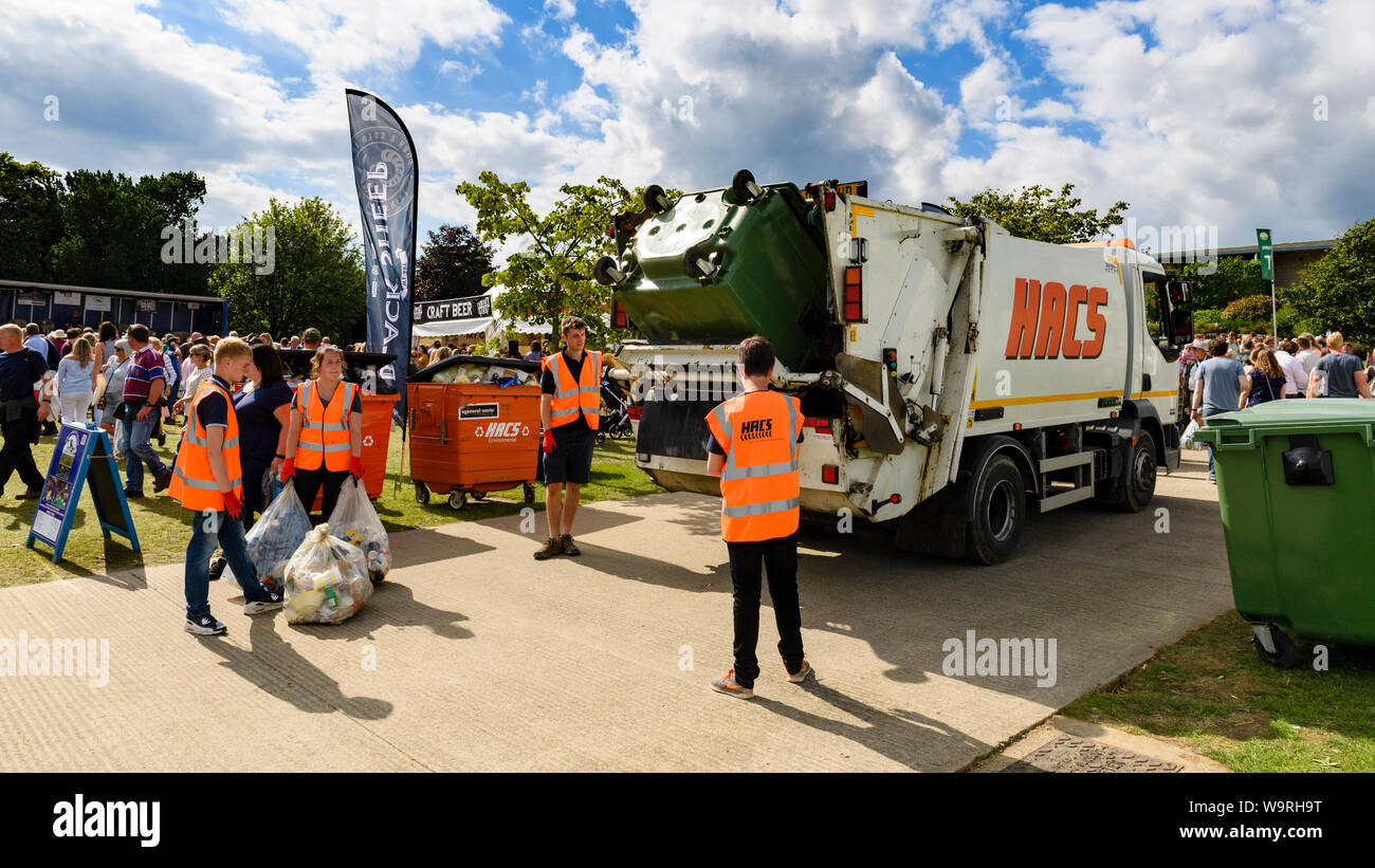 Wheelie bin emptied into waste collection dustbin lorry, bags of rubbish & refuse collectors working at busy venue - Great Yorkshire Show, England, UK Stock Photo