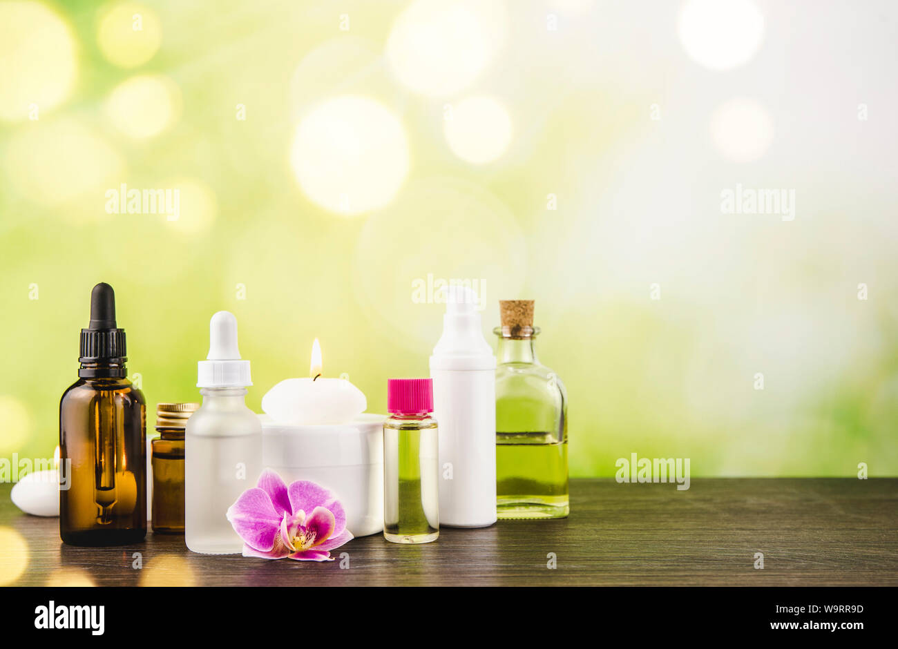Composition with lot of different size, shape and material beauty cosmetics products bottles arrangement on wooden table with green bokeh studio backg Stock Photo