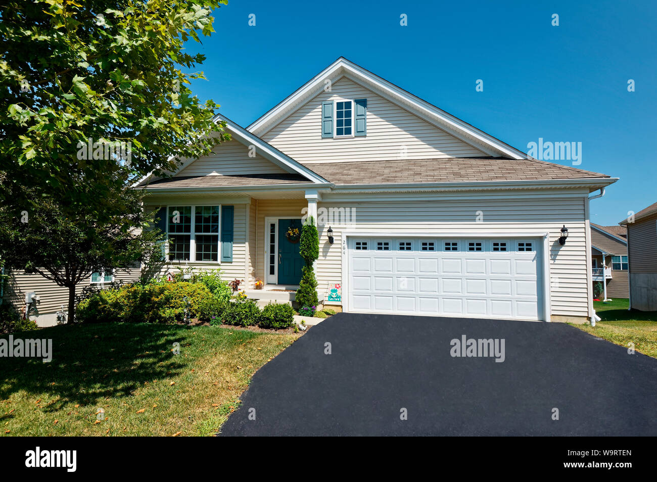 single house; front, double garage doors; windows; door; driveway; tree; shrubs, shutters, Valley Township; PA; Pennsylvania; summer; PR; horizontal Stock Photo