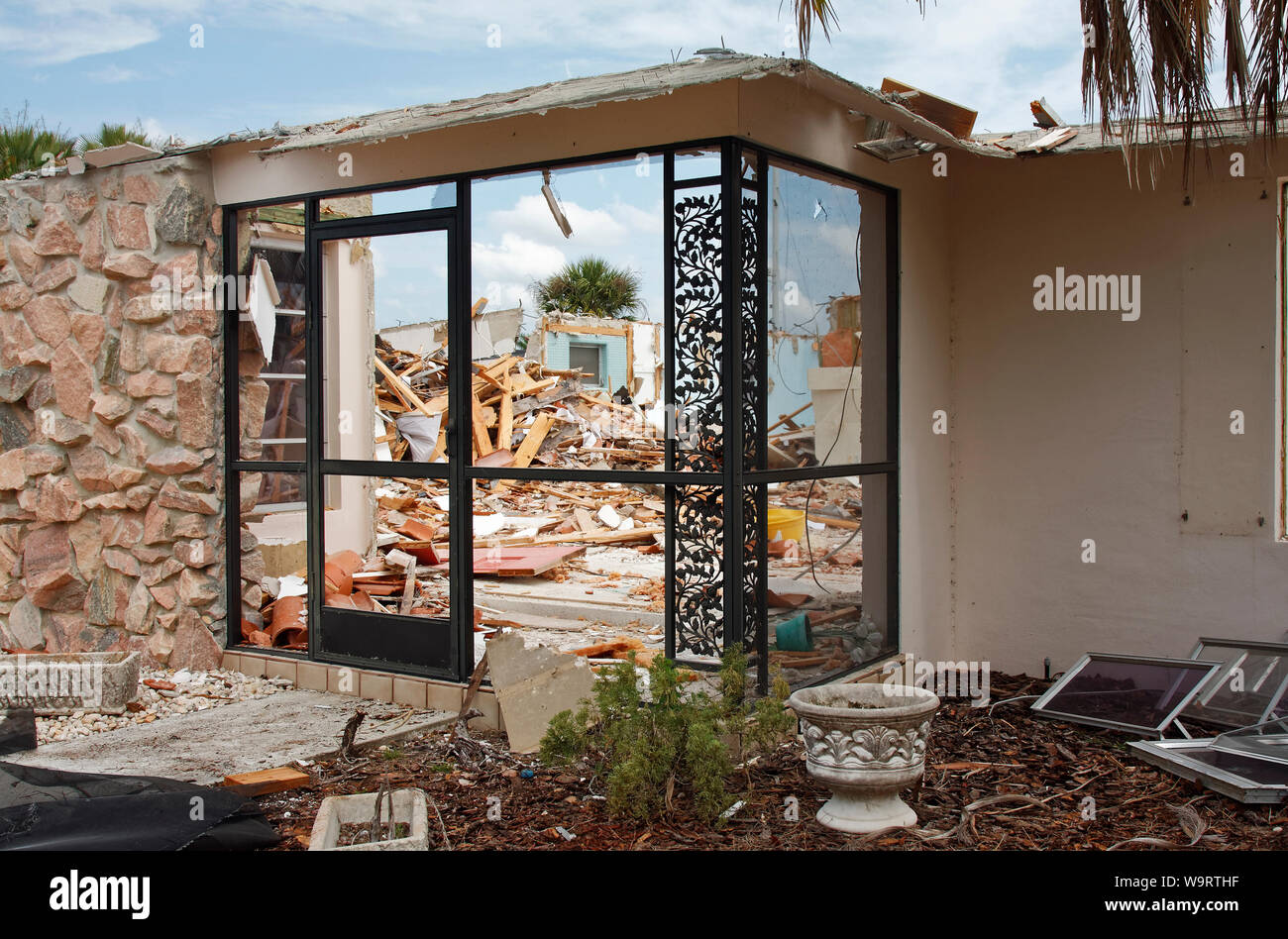 house being demolished, front wall standing, debris piles inside, roof gone, destruction, horizontal; PR Stock Photo