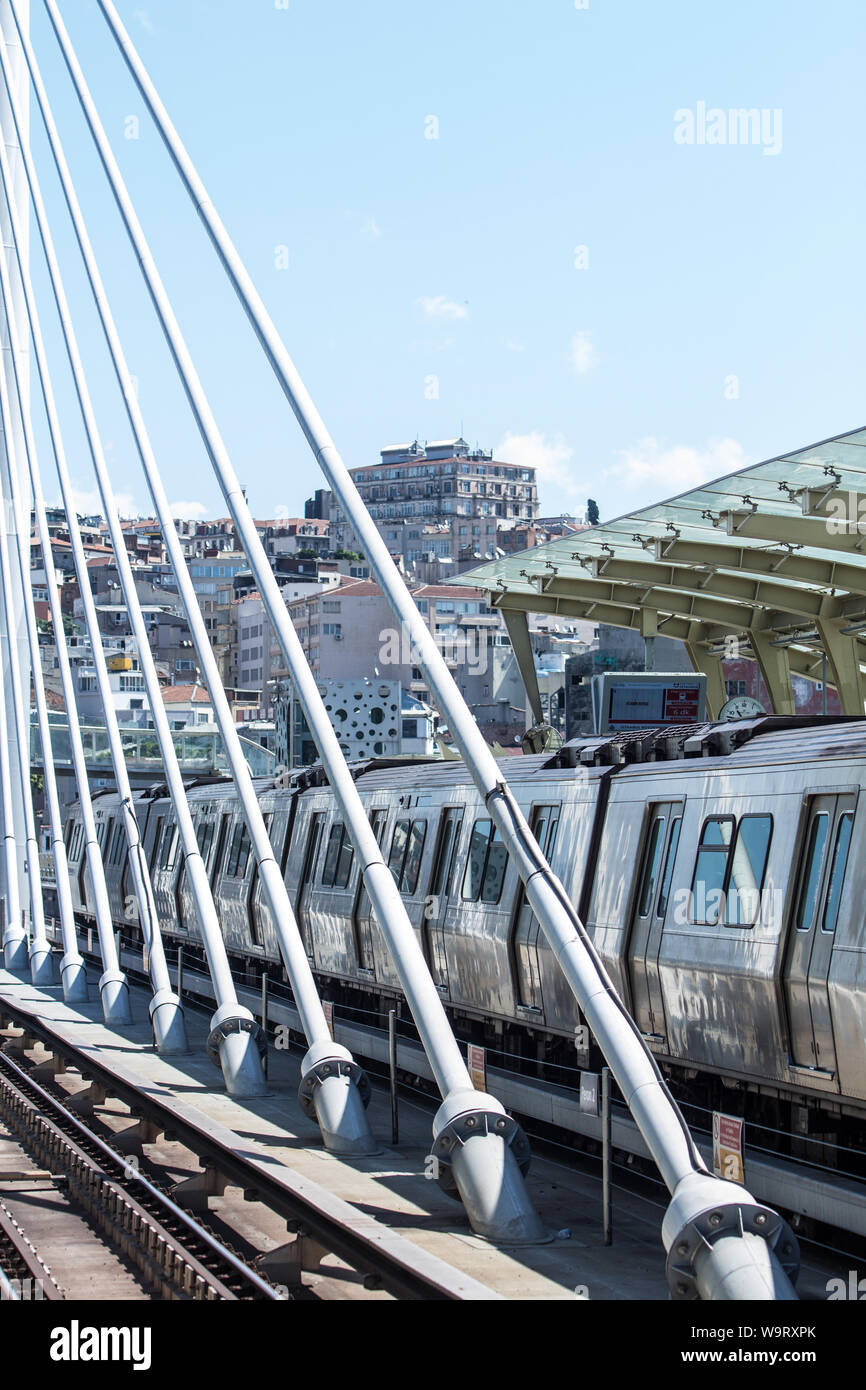 A metro train docked at the station at the suspension bridge over the Golden Horn. In the background the historical administrative building for tunnel Stock Photo