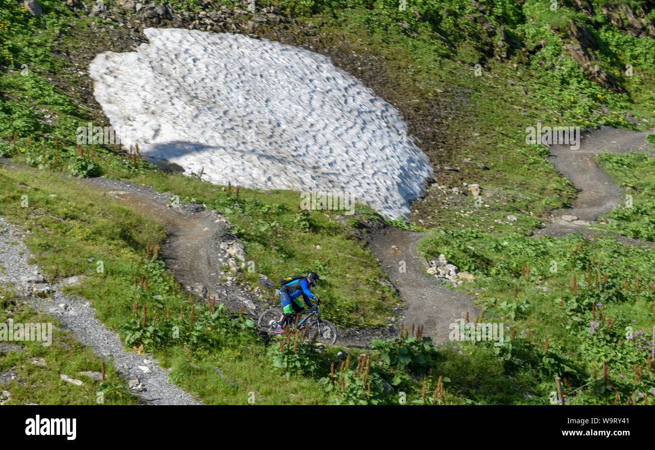 Jochpass, Switzerland - 4 august 2018: man on his mountain bike going down the path from Jochpass over Engelberg in the Swiss Alps Stock Photo
