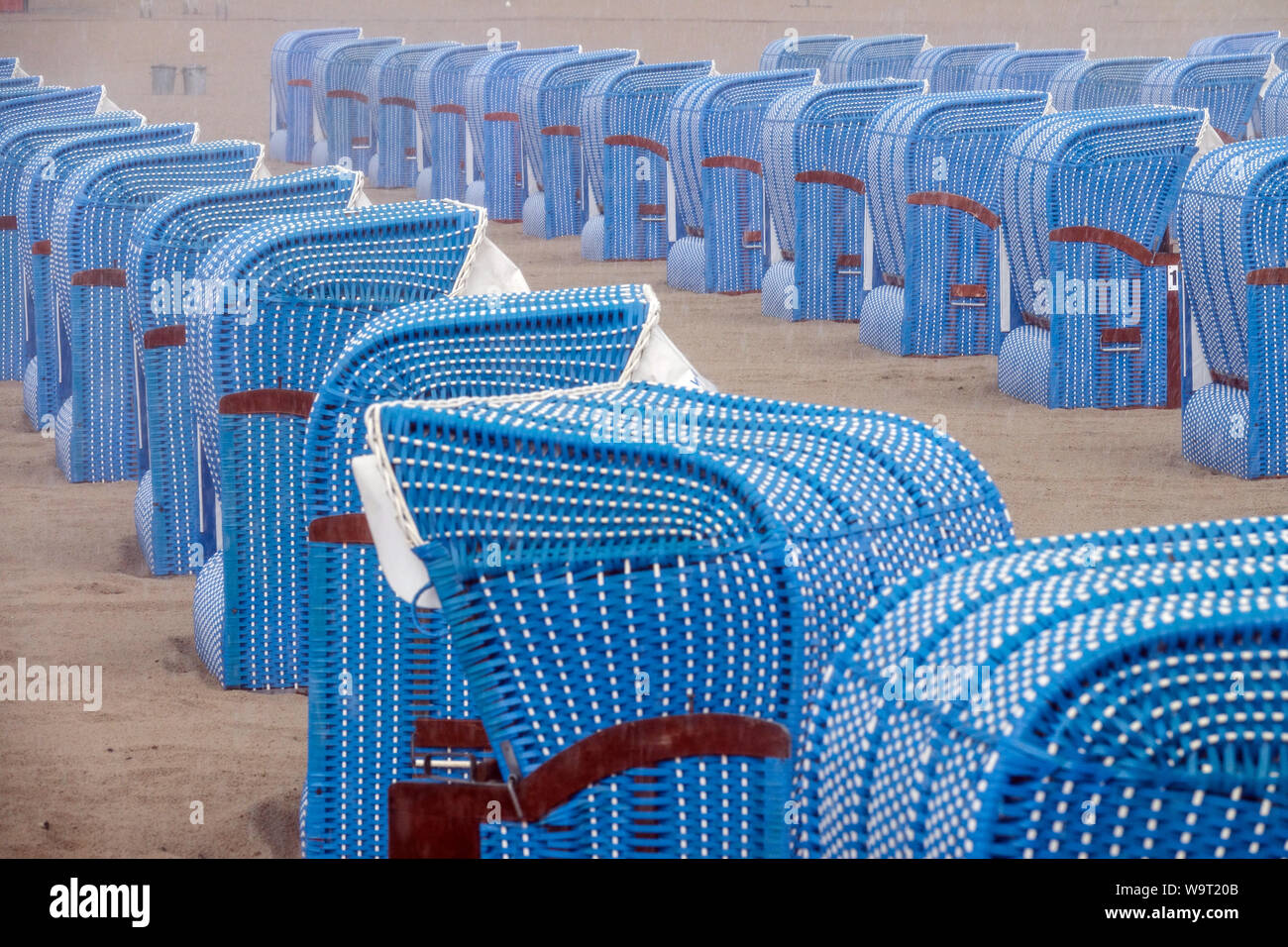 Blue wicker beach chairs, wicker baskets in a row on the sandy beach in Warnemunde, Germany Stock Photo