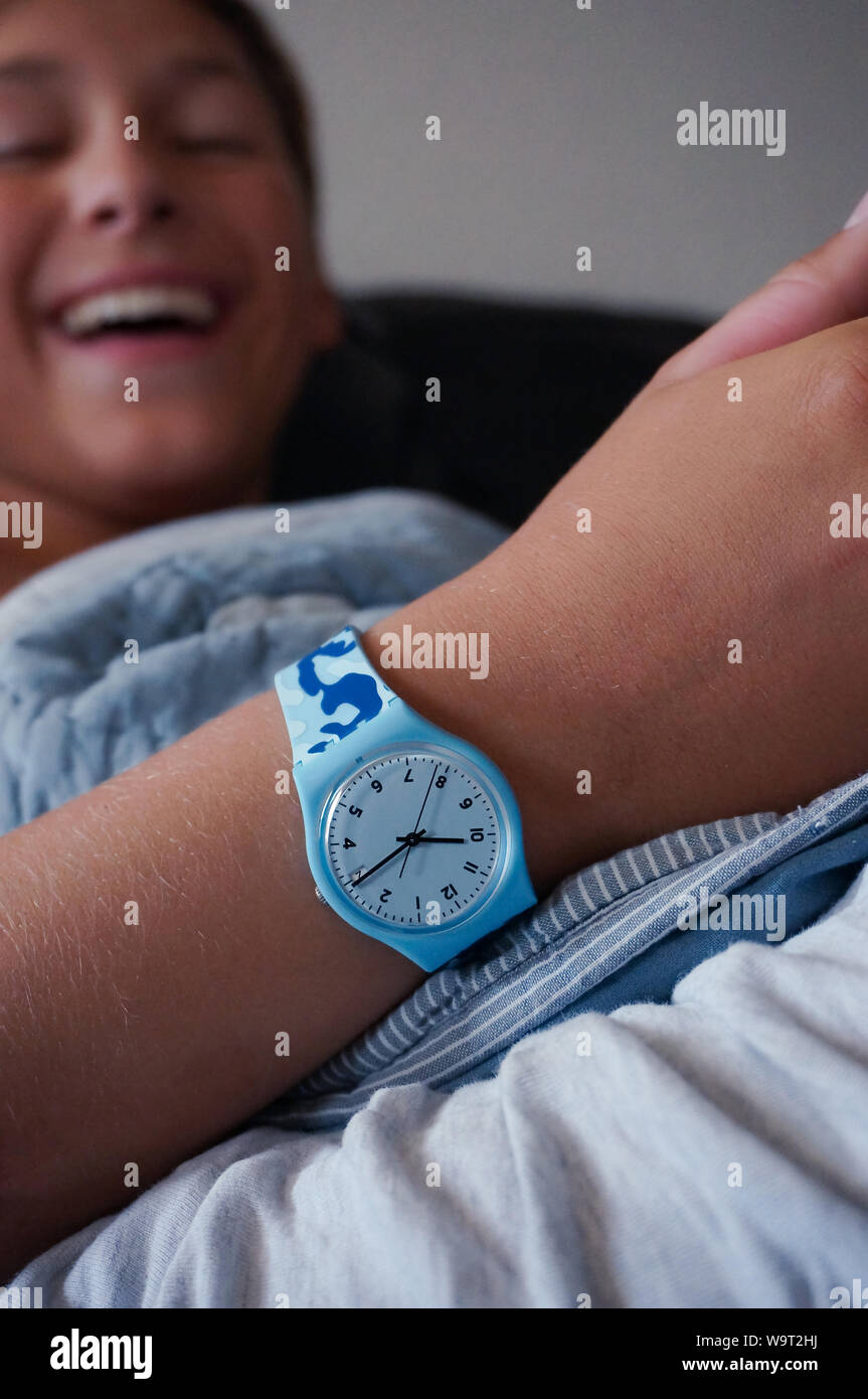 Alicante, Spain - August, 2019: Blue rubber Swatch watch on wrist of smiling teenager Stock Photo
