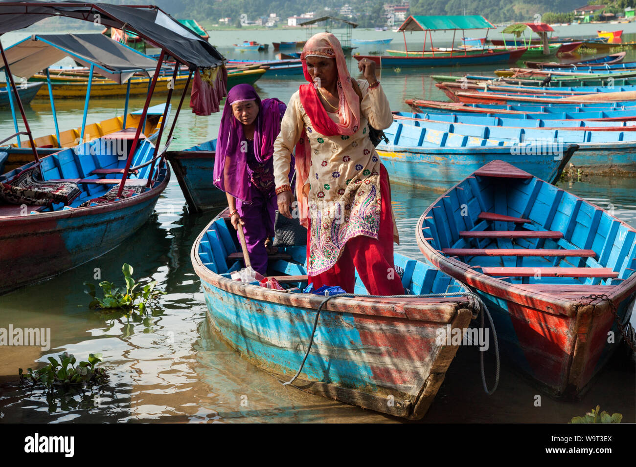 Women climb out of a small fishing boat on the lake at Pokhara Stock Photo
