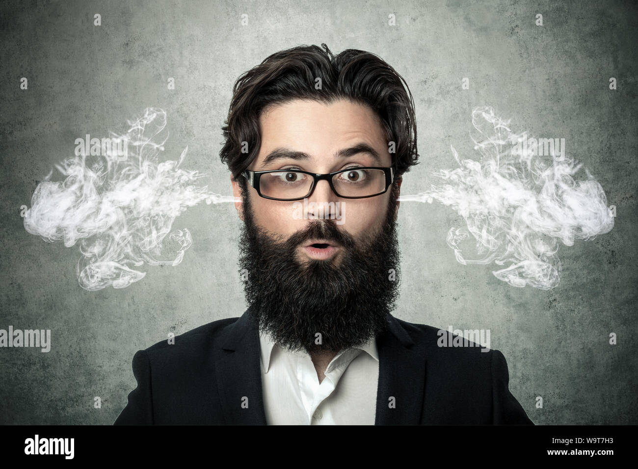 bearded surprised man, blowing steam coming out of ears, over gray background, negative human emotions, facial expression, feelings Stock Photo